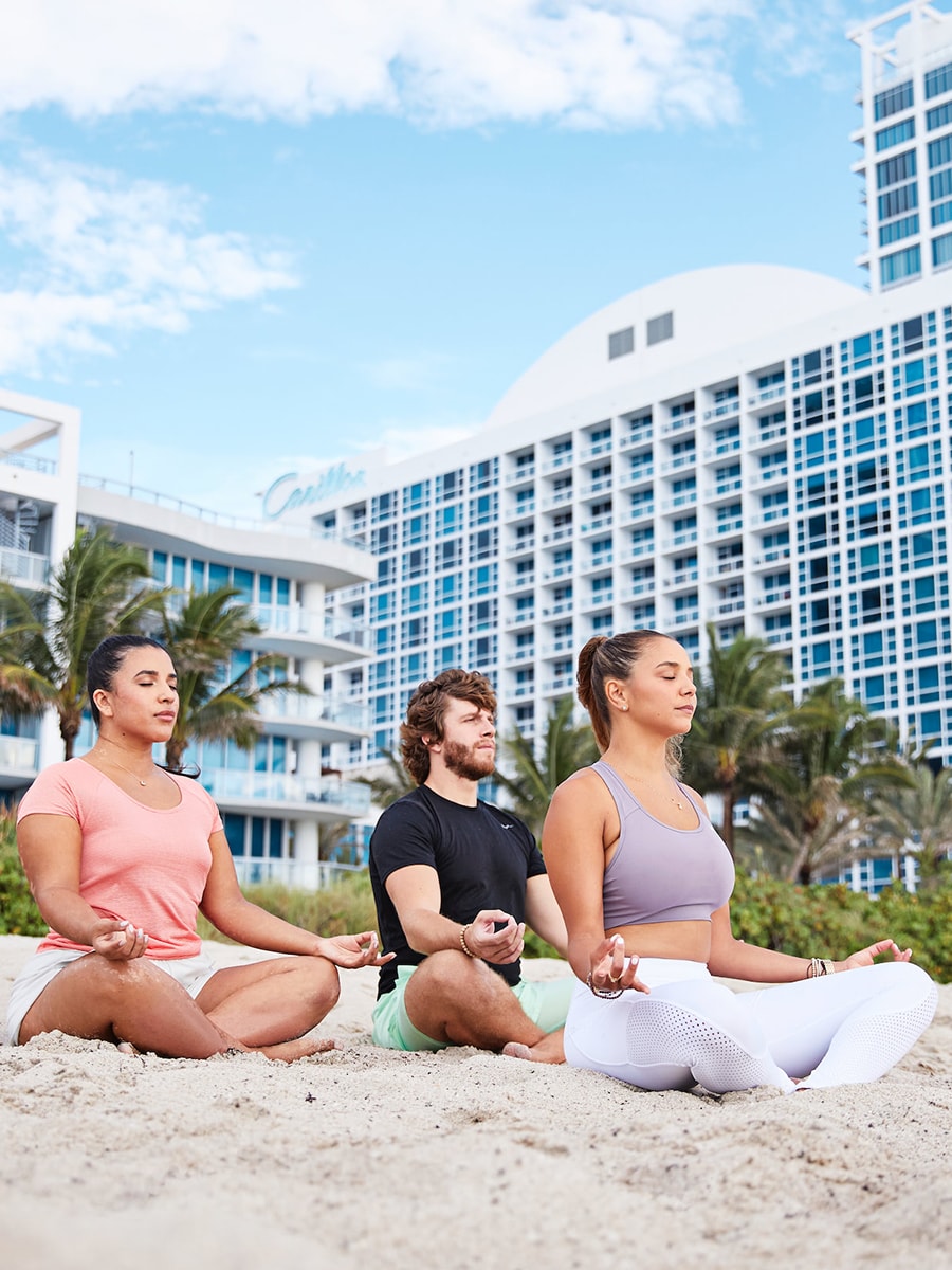 3 people doing yoga on the beach